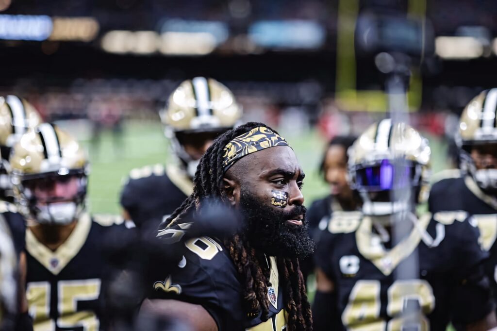 Demario Davis center framed with New Orleans Saints teammates in black and gold uniforms stadium lights Wallpaper