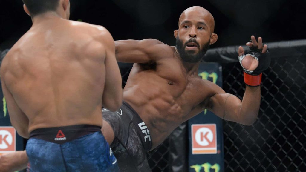 Demetrious Johnson delivers a precise kick to Henry Cejudo in UFC 227 Octagon action wallpaper