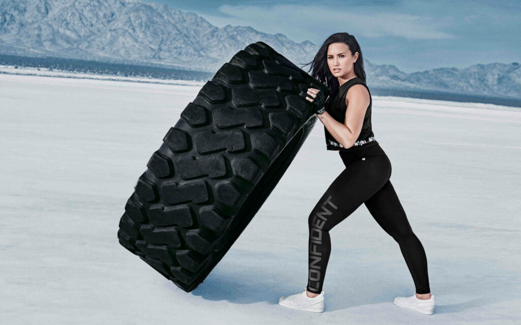 Demi Lovato Empowering Tire Flip Wallpaper: Strength & Determination