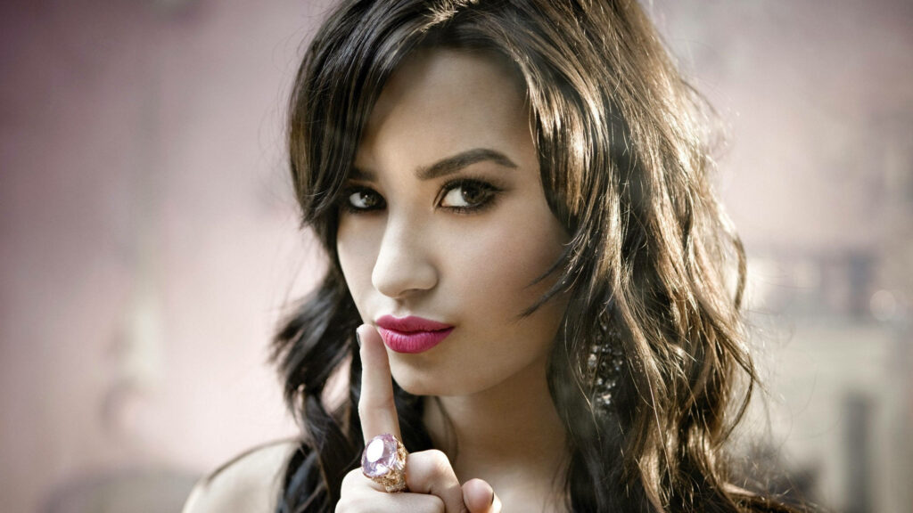 Demi Lovato Wallpaper: Confident Silence Gesture on Soft Background
