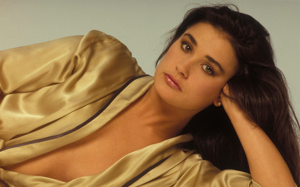 Demi Moore in a silky gold robe with soft natural light and warm tones highlighting elegance Wallpaper