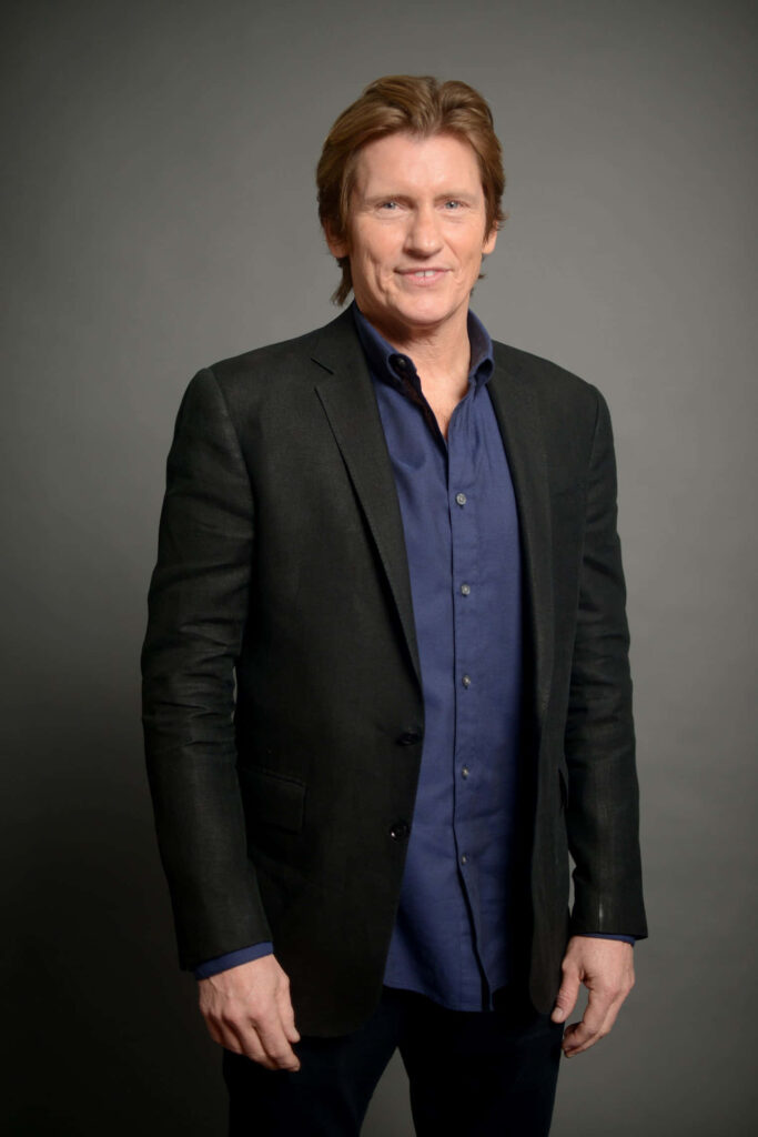 Denis Leary confident portrait navy shirt dark blazer soft lighting gray background professional look Wallpaper