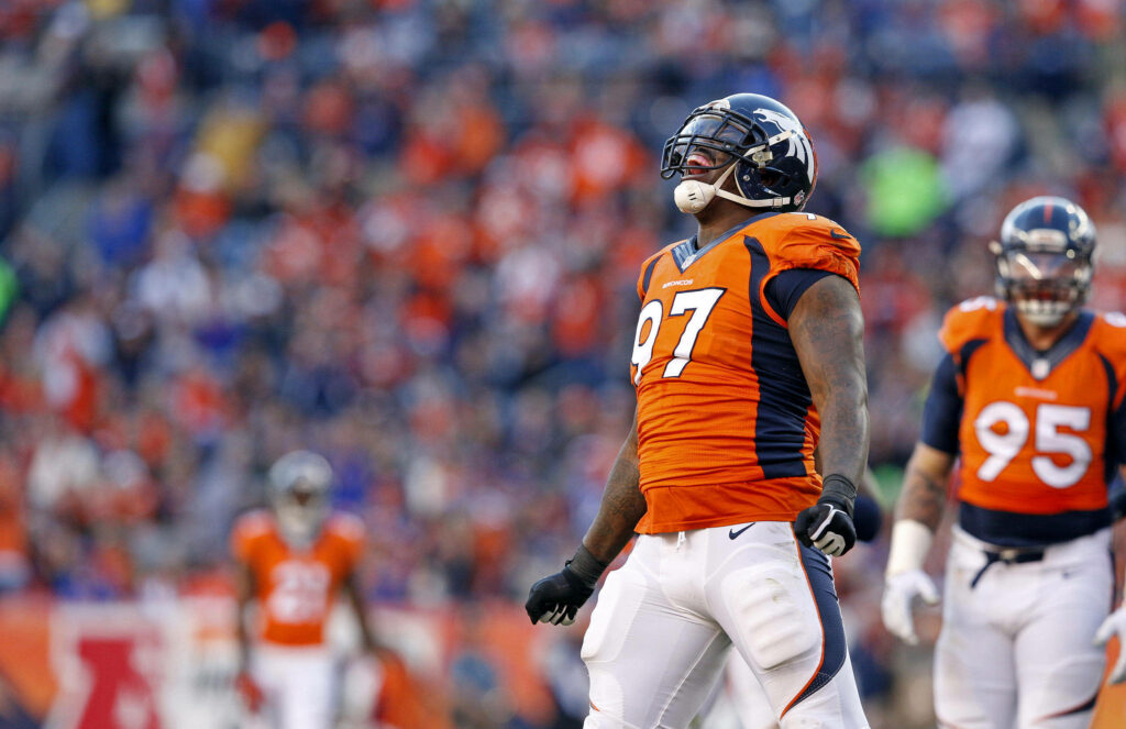 Denver Broncos player roaring in orange celebrating victory with vibrant stadium fans background Wallpaper