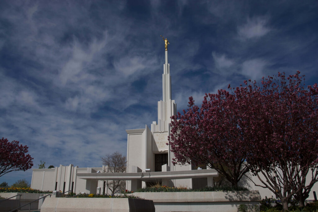 Mormon Temple Denver with vibrant blooming trees under dramatic cloudy sky scenic wallpaper background
