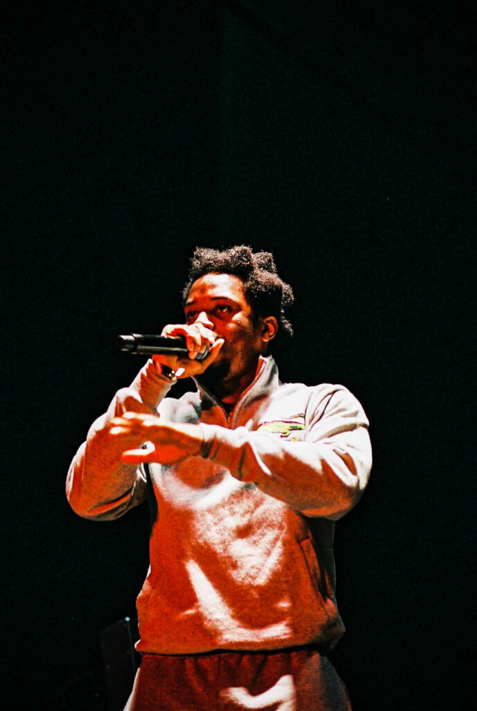 Denzel Curry performing live on stage with dramatic lighting in a dynamic hip-hop concert setting Wallpaper