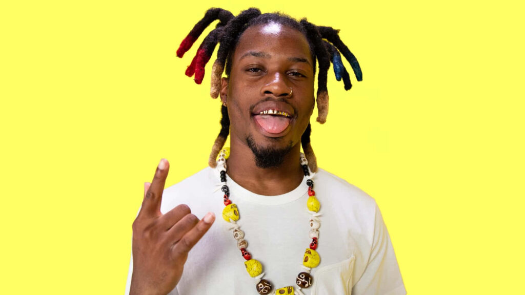 Denzel Curry vibrant wallpaper multicolored dreadlocks yellow background playful hip hop pose