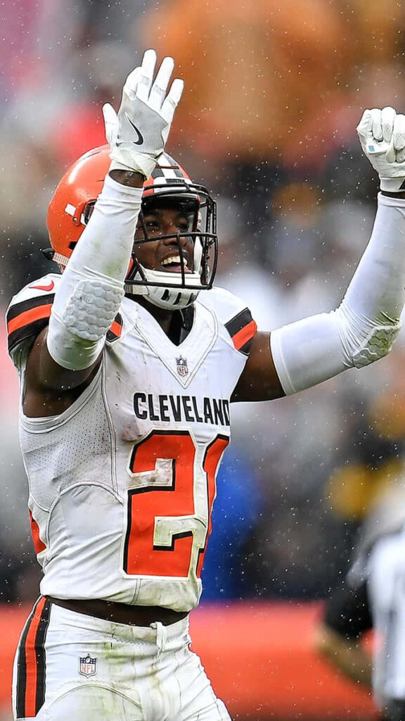 Denzel Ward Cleveland Browns celebrating successful pass in orange white uniform on rainy field Wallpaper