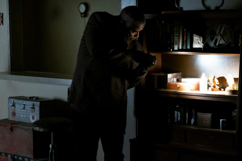 Denzel Washington intensely searching dim room with flashlight inspecting shelf wallpaper background