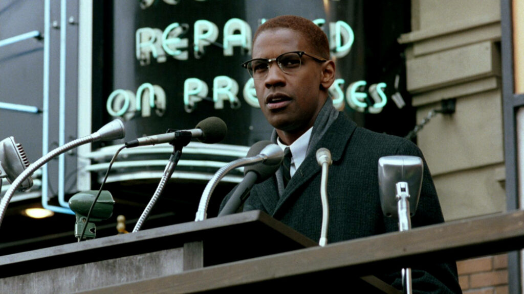 Denzel Washington delivering a powerful speech at podium with microphones urban neon backdrop wallpaper