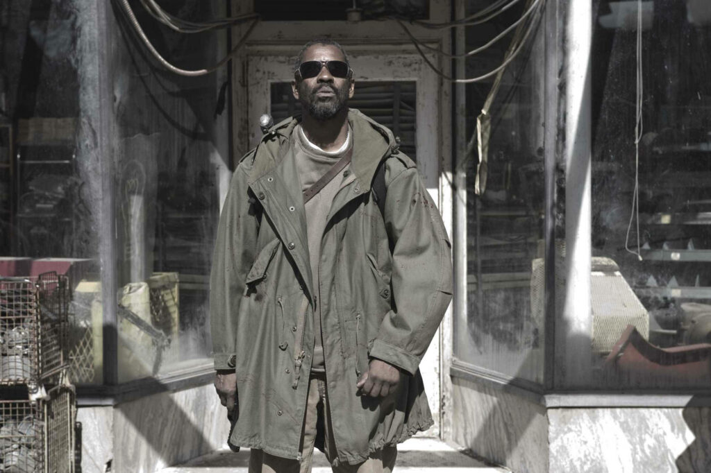 Denzel Washington in rugged attire under sunlight with dramatic urban backdrop powerful scene Wallpaper