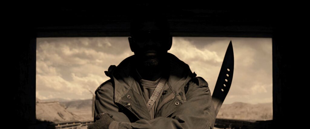 Denzel Washington silhouette with machete in rugged landscape dramatic cinematic wallpaper