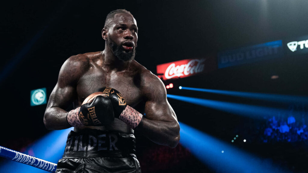 Deontay Wilder intense and powerful in boxing ring with dramatic lighting and crowd energy Wallpaper