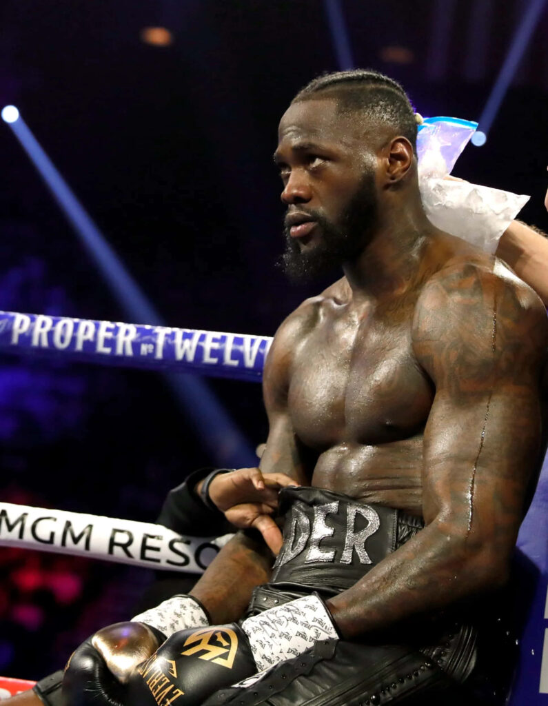 Deontay Wilder sits ringside recovering during intense boxing match with his team assisting Wallpaper