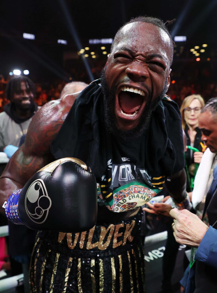 Deontay Wilder triumphant boxing celebration with vibrant colors and energetic championship crowd Wallpaper