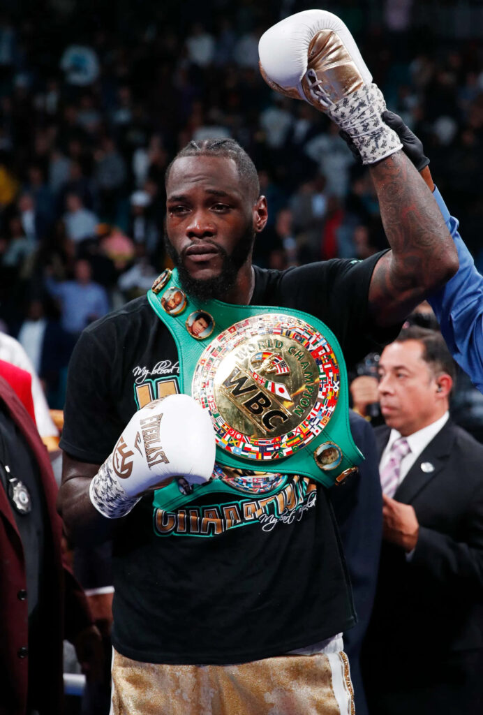 Deontay Wilder celebrates boxing victory raising fist wearing green gold WBC championship belt Wallpaper