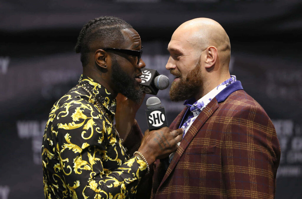 Deontay Wilder and Tyson Fury intense stare-down holding microphones boxing wallpaper background