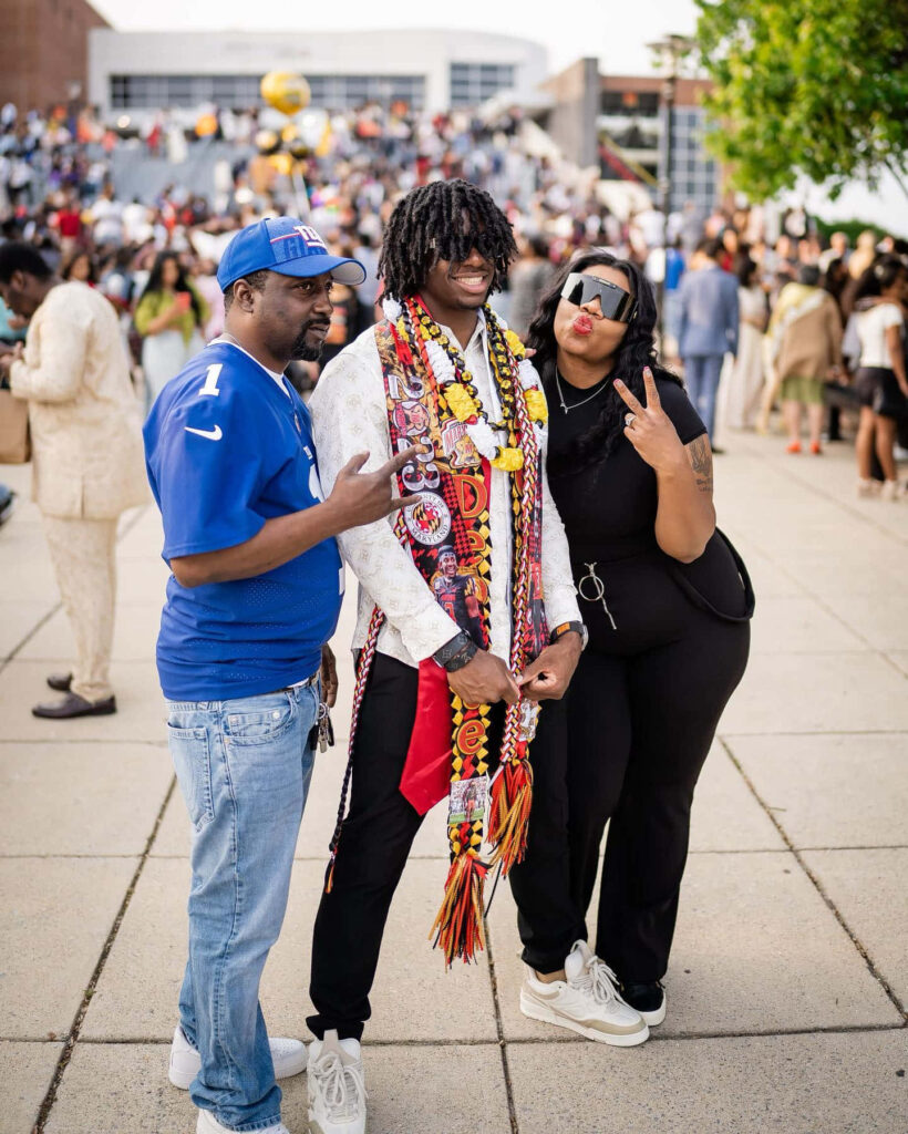 Deonte Banks graduation celebration outdoors with friends family vibrant leis bright smiles Wallpaper
