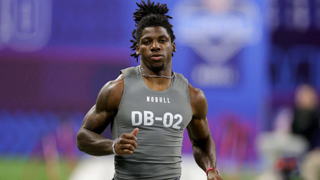 Deonte Banks running drill NFL Combine athletic physique focus blue purple background wallpaper