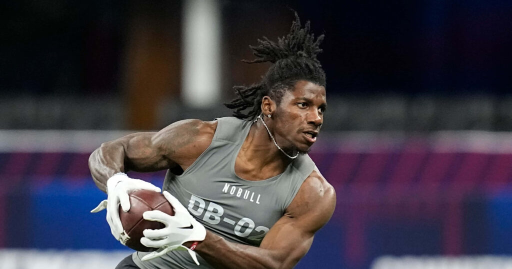 Deonte Banks sprinting with football at combine showing focus strength and athleticism indoors Wallpaper