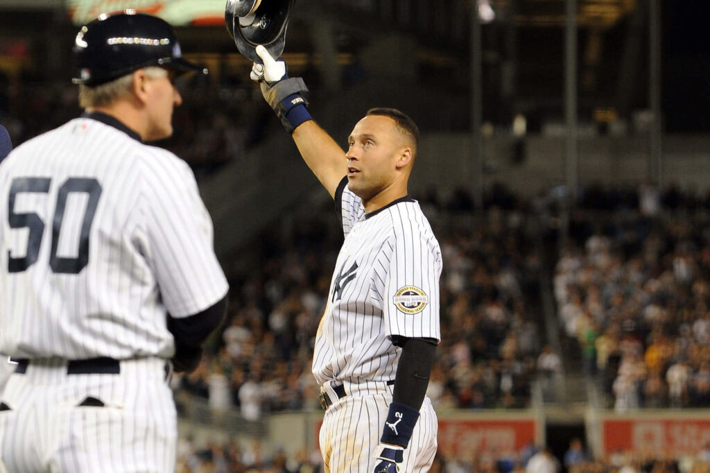 Derek Jeter in pinstripe uniform raising helmet at Yankee Stadium celebrating with fans wallpaper