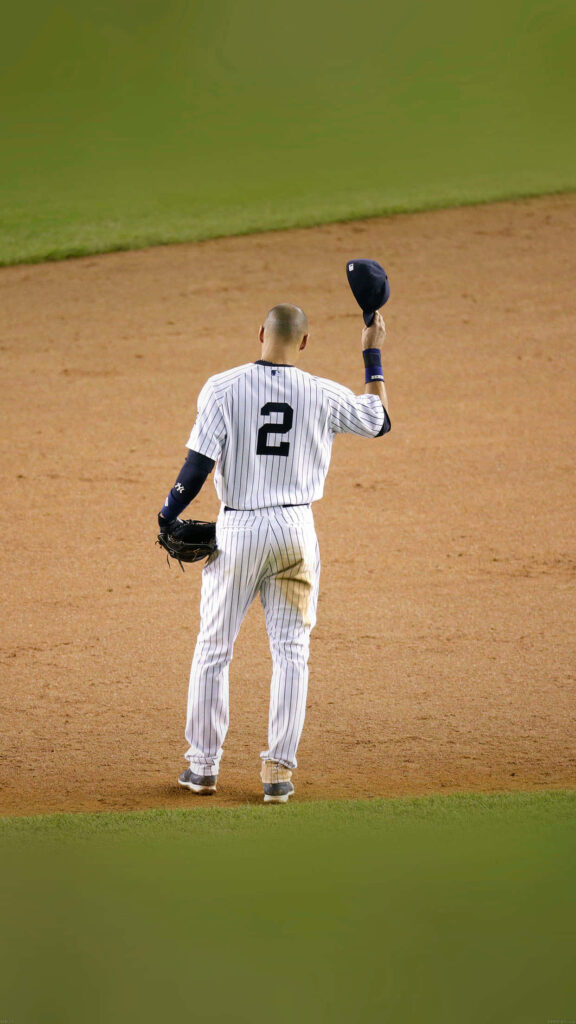 Derek Jeter in Yankees pinstripe uniform raising cap on baseball field celebrating number 2 legacy Wallpaper