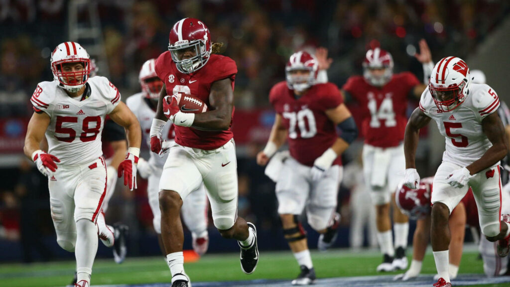 Derrick Henry Red Titan in Alabama football uniform powering through defense intense game action Wallpaper