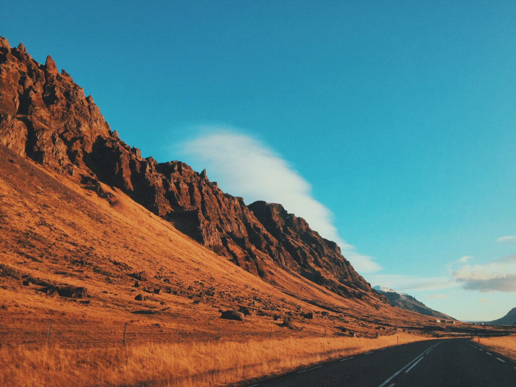 Breathtaking Desert Adventure Wallpaper: Vast Road & Rugged Cliffs