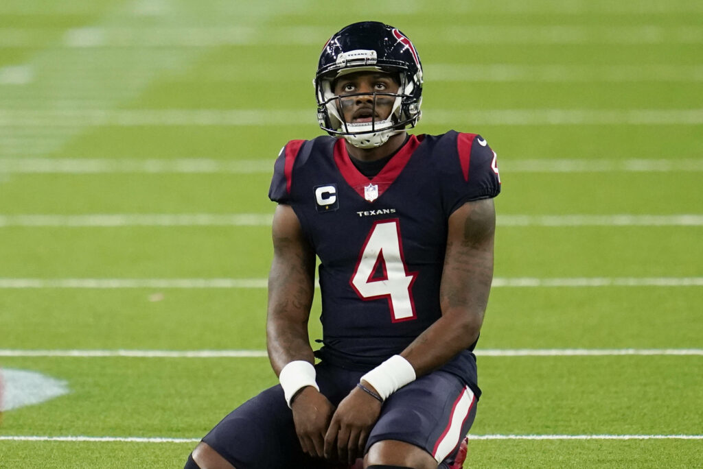 Deshaun Watson in Houston Texans uniform sitting on green turf at NRG Stadium reflecting during game Wallpaper