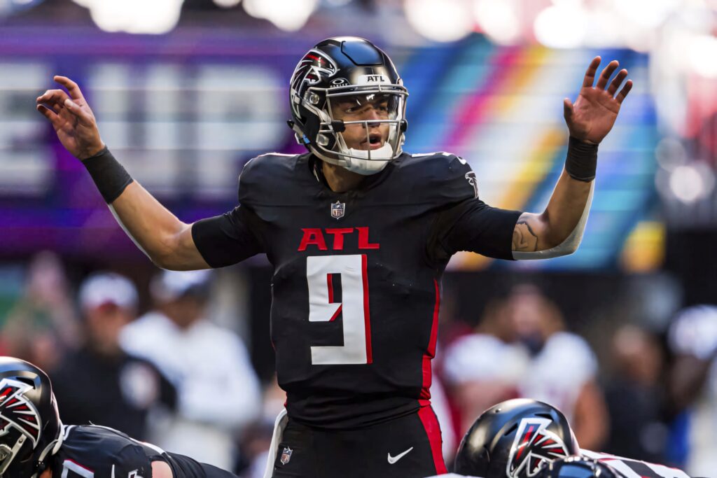 Desmond Ridder Atlanta Falcons quarterback in black and red uniform mid-action vibrant stadium wallpaper