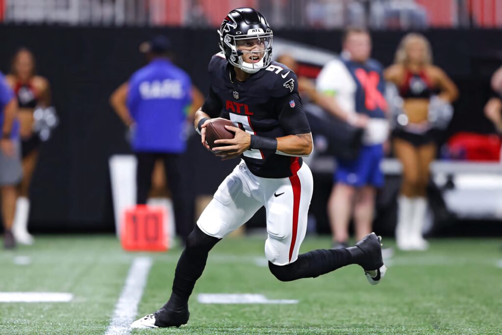 Desmond Ridder Atlanta Falcons quarterback poised to pass in black red white uniform on field Wallpaper