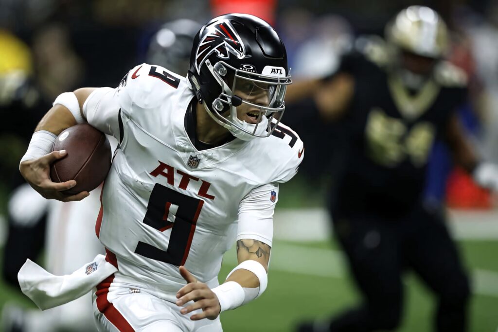 Desmond Ridder Atlanta Falcons quarterback scrambling with football in intense game action wallpaper