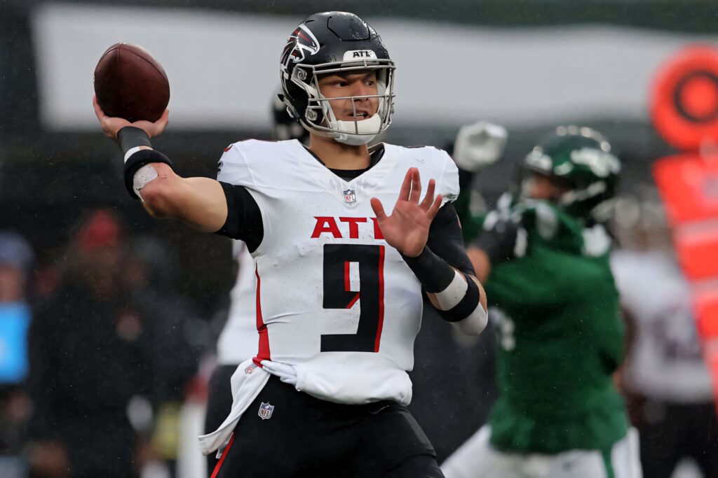 Desmond Ridder Atlanta Falcons quarterback throwing football in white red uniform on rainy field Wallpaper