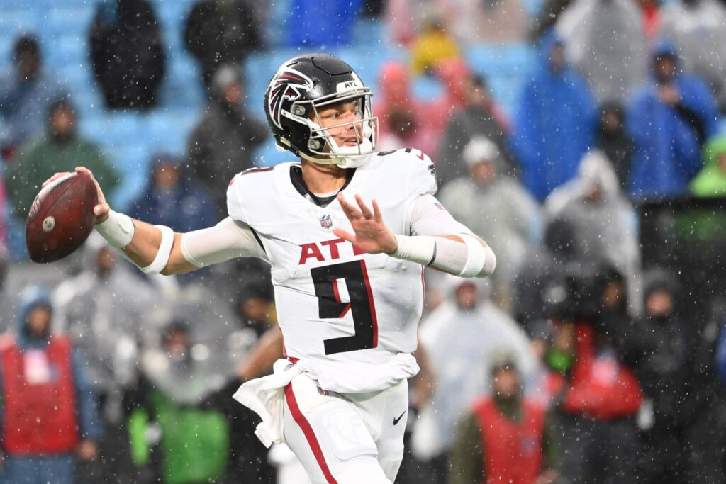 Desmond Ridder Falcons quarterback in white uniform throwing football in rainy stadium action Wallpaper