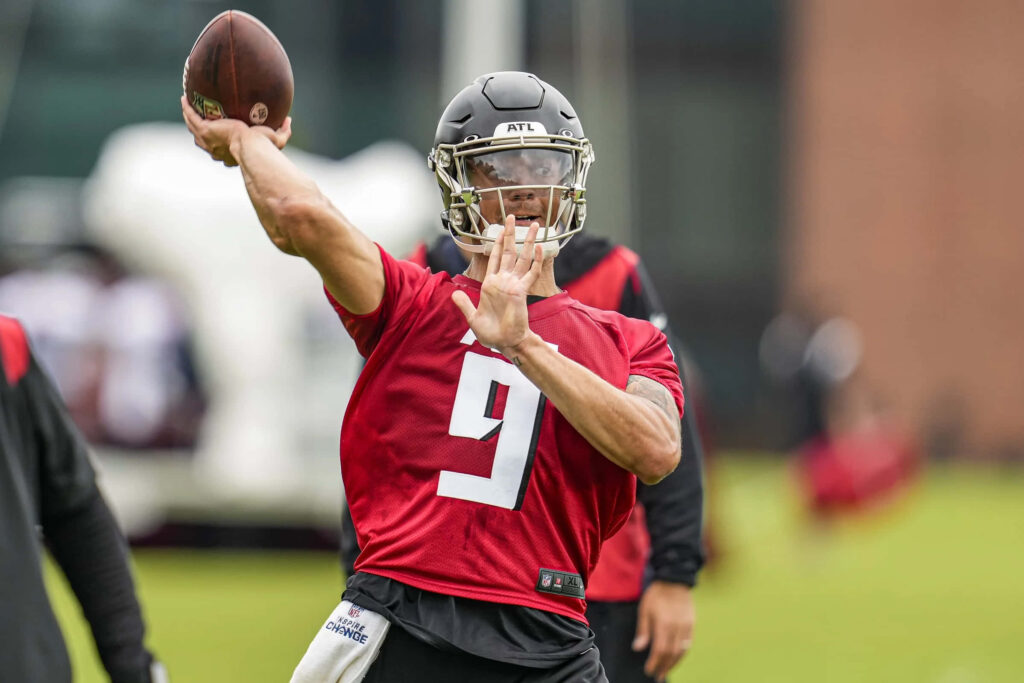 Desmond Ridder throwing a pass in Atlanta Falcons red jersey and black helmet during training Wallpaper