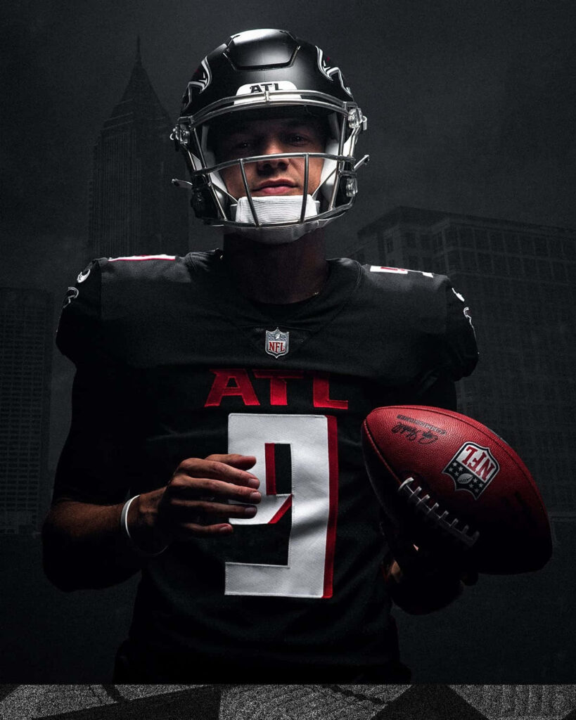Desmond Ridder Atlanta Falcons quarterback in full gear with dramatic black red cityscape background Wallpaper
