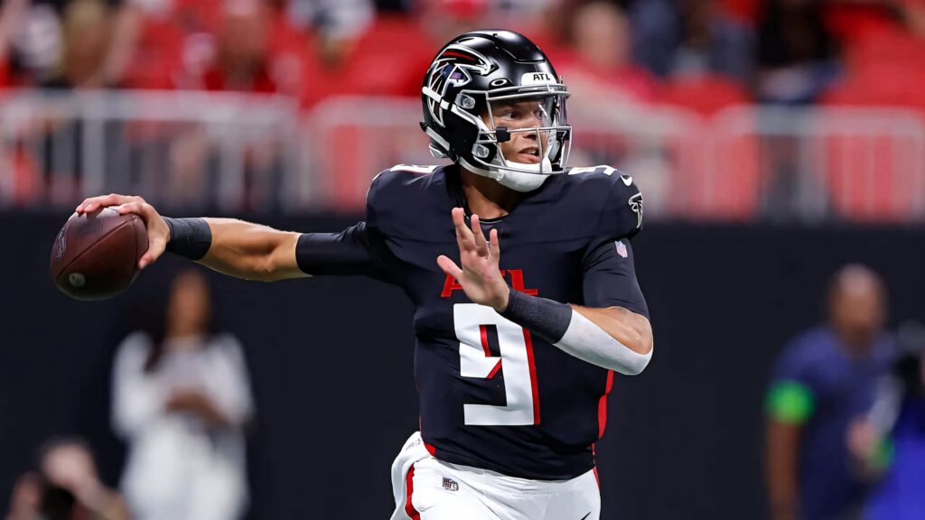 Desmond Ridder Atlanta Falcons quarterback throwing football in black and red uniform stadium background Wallpaper
