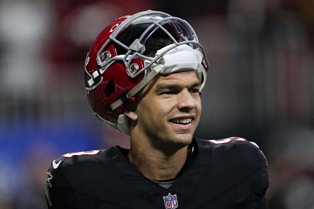 Desmond Ridder confident smile Atlanta Falcons uniform football helmet bright stadium lights Wallpaper