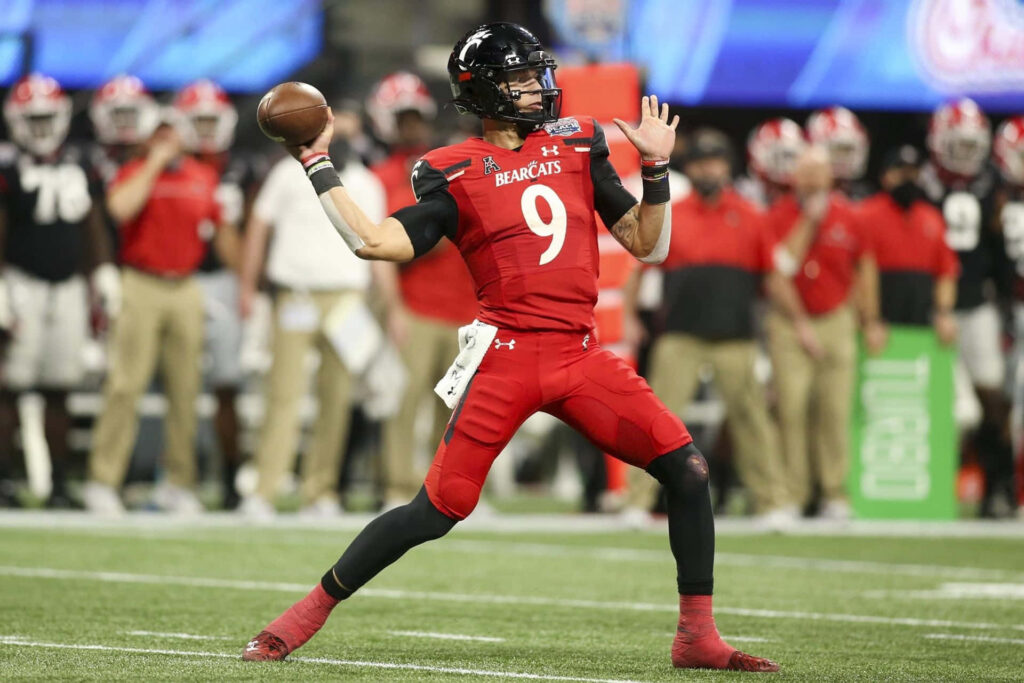 Desmond Ridder Cincinnati Bearcats quarterback poised to throw in vibrant red and black uniform Wallpaper