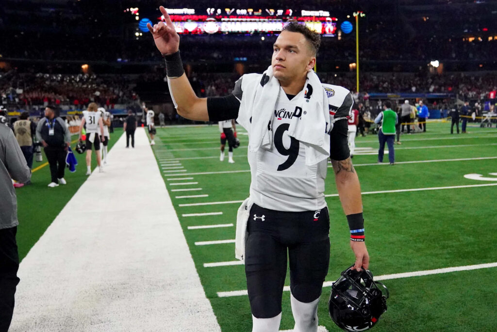 Desmond Ridder Cincinnati football player saluting fans on field in black white uniform number 9 Wallpaper