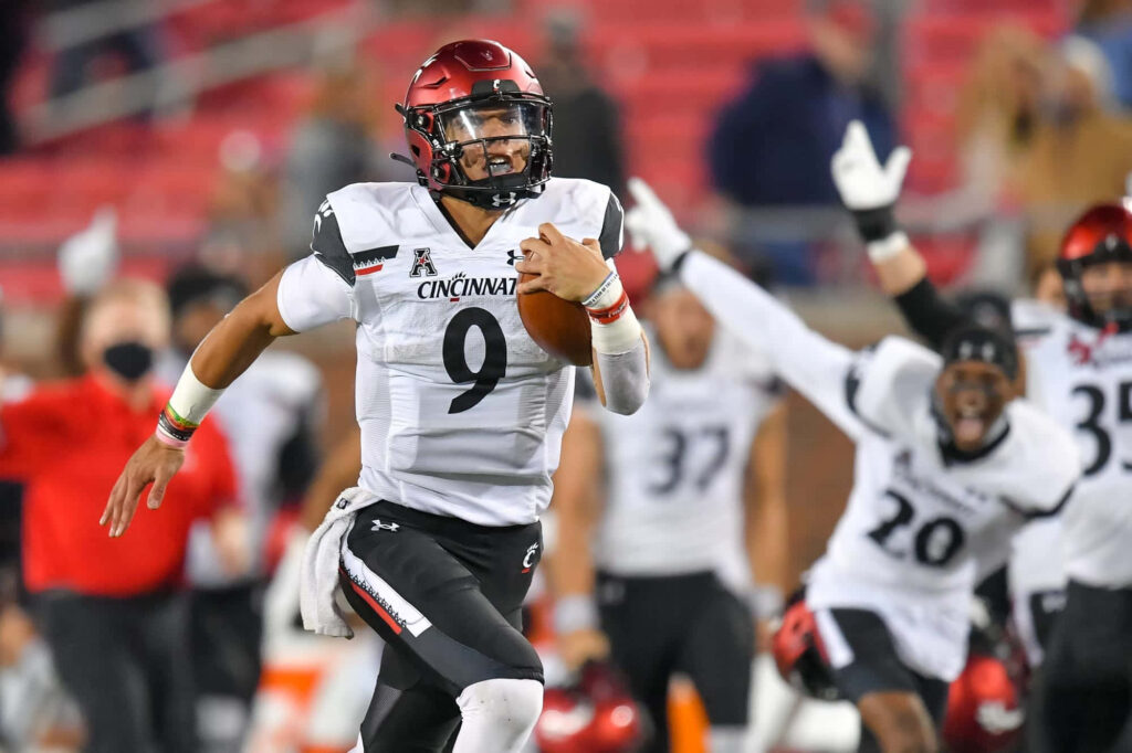 Desmond Ridder Cincinnati quarterback running with ball in white red uniform intense game action Wallpaper