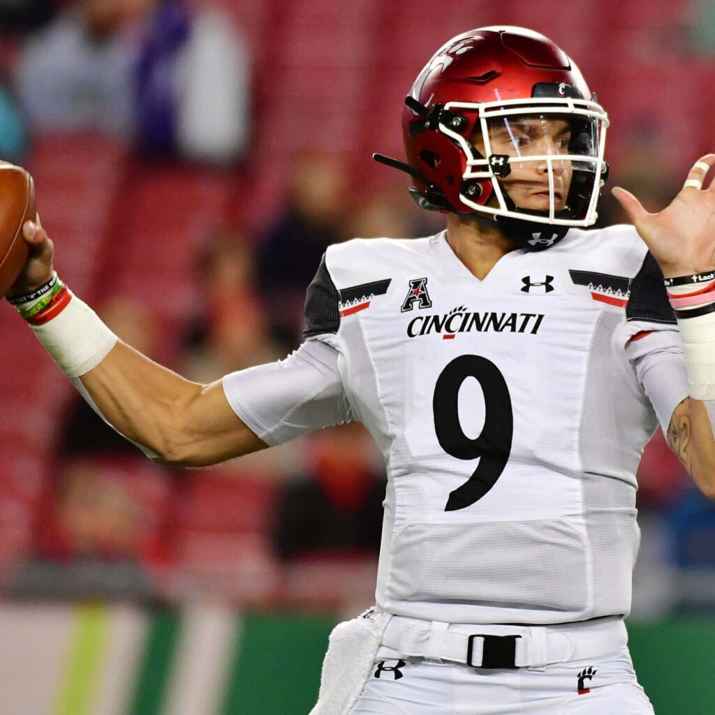 Desmond Ridder Cincinnati quarterback in white uniform delivering intense game action pass Wallpaper