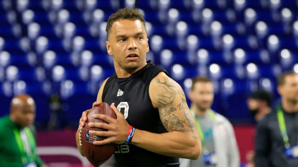 Desmond Ridder focused gripping football during indoor quarterback training session with blue seats Wallpaper