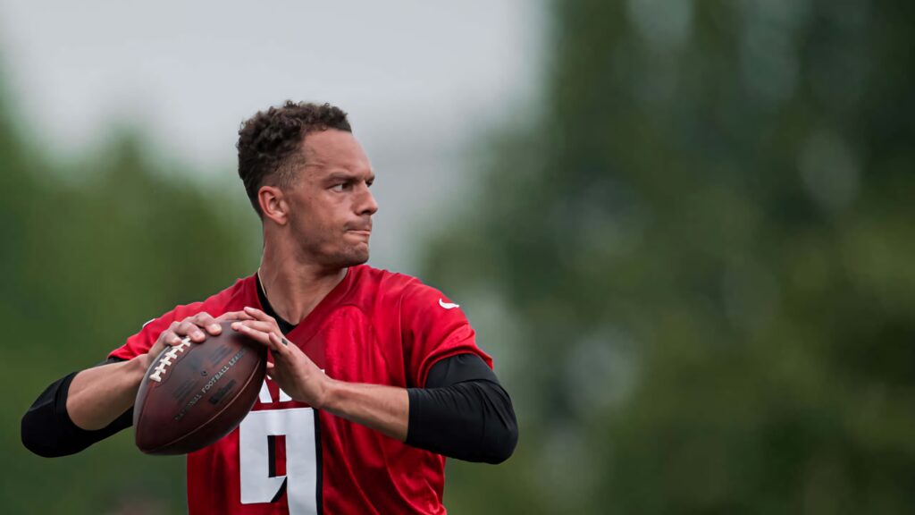 Desmond Ridder in red jersey focused throwing football during outdoor quarterback drill wallpaper
