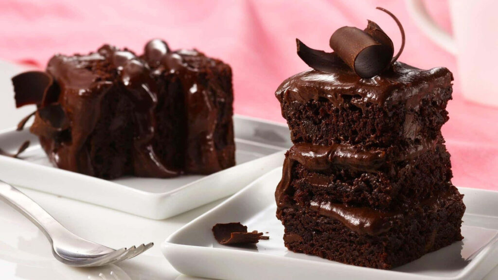 Serving Decadent Delights: Fudgy Chocolate Cakes on a Sweet Pink Canvas Wallpaper