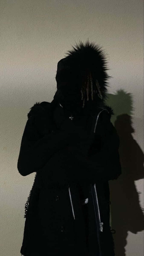 Destroy Lonely in shadowy black fur hood moody textured wall wallpaper background edgy style