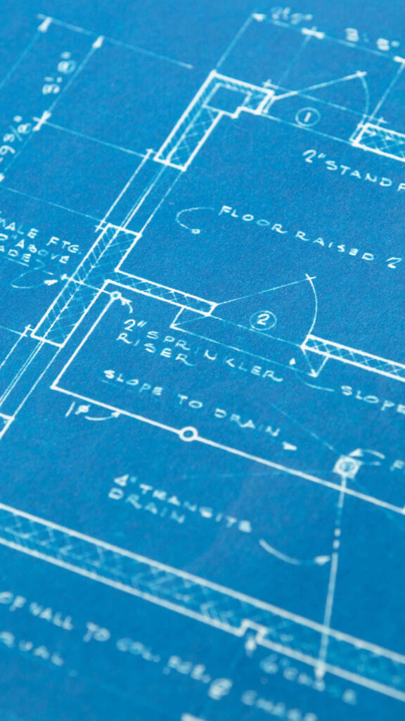 Close-up architectural blueprint with white technical drawings and handwritten notes on blue background Wallpaper