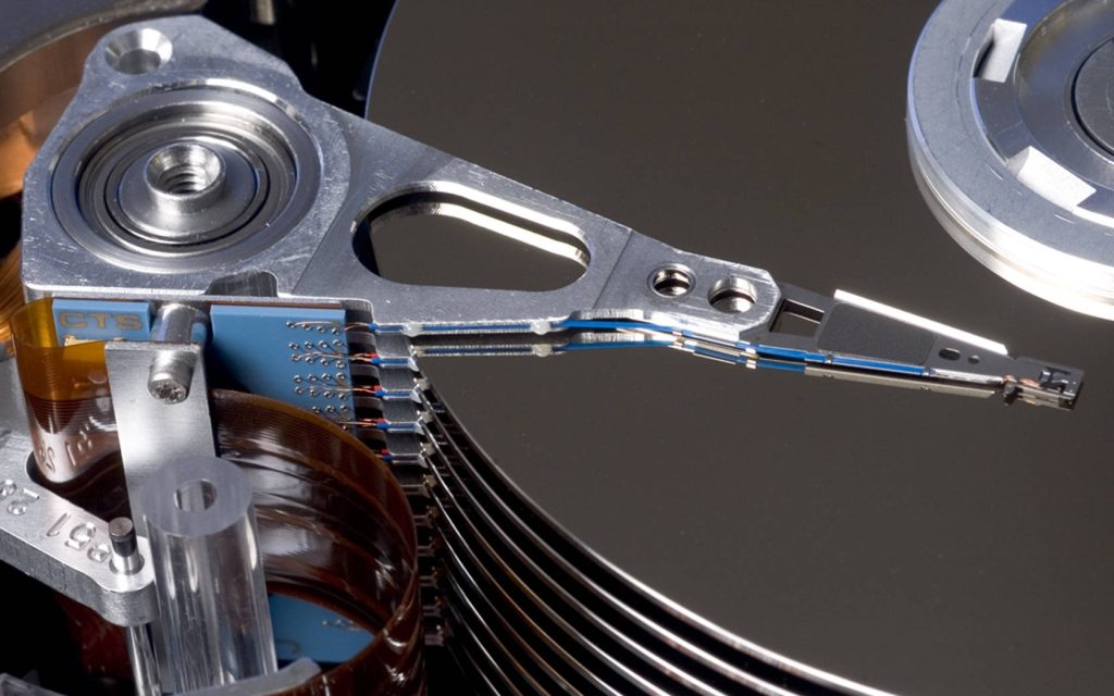 Close-up macro of a polished hard disk drive actuator arm over shiny data platters industrial design Wallpaper