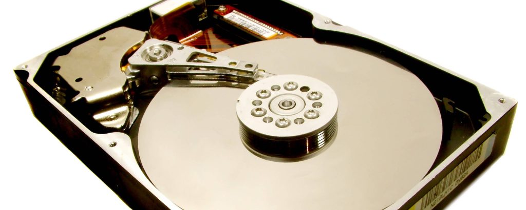 Macro view of hard drive internal parts including silver platter actuator arm and spindle motor Wallpaper