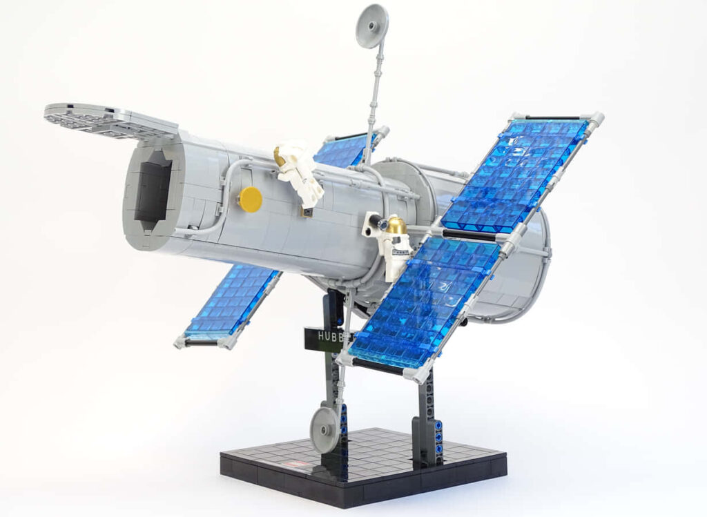 Lego Hubble Space Telescope model with detailed solar panels on display base against wallpaper