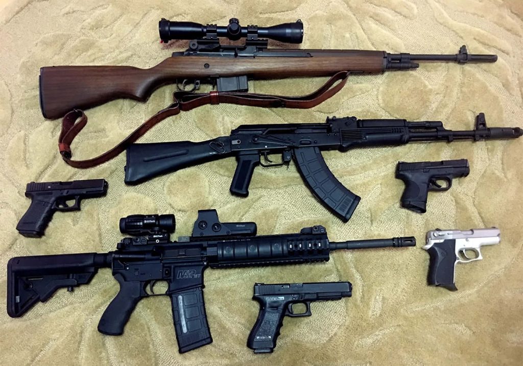 Top view gun wallpaper with M14 rifle AK pattern S&W M&P 15 and semi-automatic pistols tan background